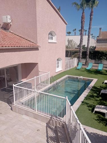 - une piscine à côté d'une maison avec des palmiers dans l'établissement Chambre 2 lits Simples Spa Piscine à la PlagePlage, à Valras-Plage