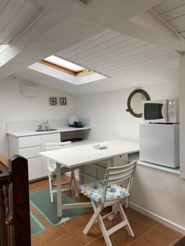 Una cocina con mesa y sillas y un microondas. en Delizioso Monolocale mansardato, en Viareggio