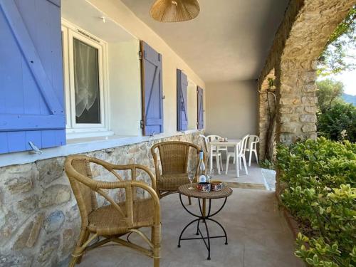 d'une terrasse avec des chaises en osier et une table sur un mur en pierre. dans l'établissement Maisonnette, à Toulon