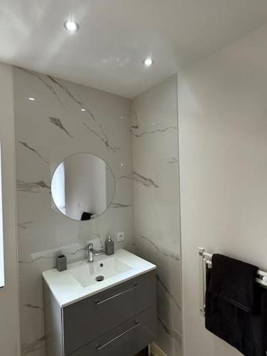 une salle de bain blanche avec un lavabo et un miroir dans l'établissement Le petit jurassien 2, à Bellefontaine