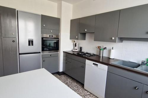 une cuisine avec des placards gris et un comptoir blanc dans l'établissement Maison arborée à Gurgy, à Gurgy