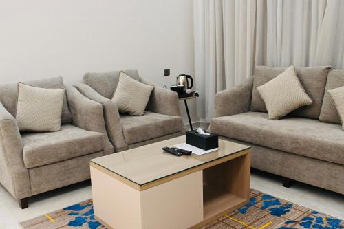 a living room with two couches and a coffee table at شقق مشراق هوم للأجنحة الفندقية in Huḑayb
