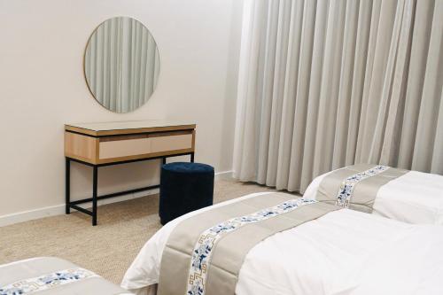 a room with two beds and a desk and a mirror at شقق مشراق هوم للأجنحة الفندقية in Huḑayb