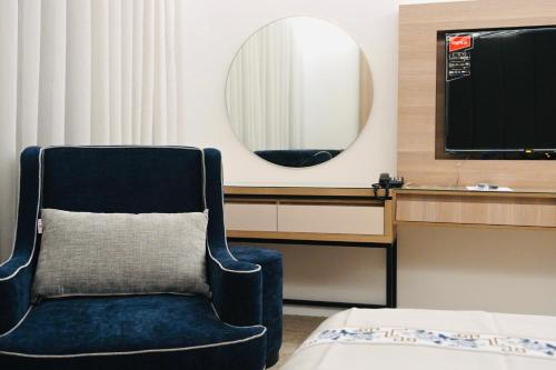 a chair in a room with a mirror and a tv at شقق مشراق هوم للأجنحة الفندقية in Huḑayb