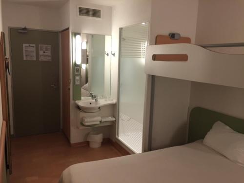a bedroom with a bed and a bathroom with a sink at Hotel Ibis Budget Deauville in Deauville