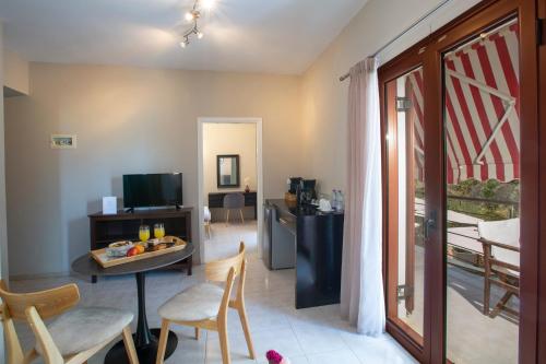 a living room with a table and chairs and a television at Athina résidence in Nydri