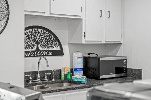 a kitchen counter with a microwave and a sink at Tranquil Tortuga Lake View Central Destin in Destin