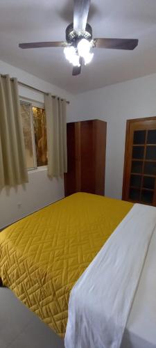 a bedroom with a yellow bed and a ceiling fan at Hotel Viajante in Tarrafal