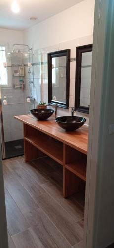 deux lavabos sur un comptoir en bois dans une salle de bain dans l'établissement Les Coteaux de Bon-Encontre, à Bon-Encontre