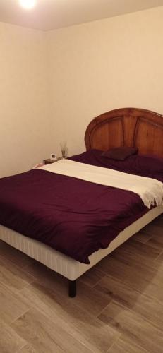 une chambre avec un grand lit avec une tête de lit en bois dans l'établissement Les Coteaux de Bon-Encontre, à Bon-Encontre