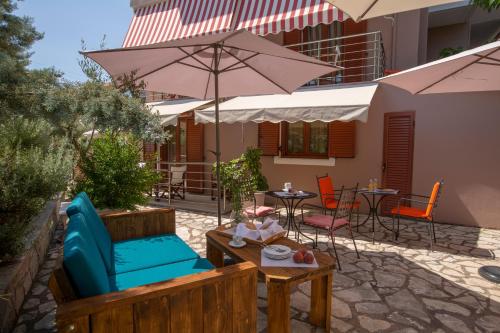 a patio with an umbrella and chairs and tables at Athina résidence in Nydri