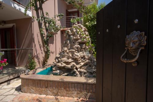 a fountain in front of a building with a fence at Athina résidence in Nydri