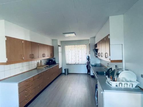 a large kitchen with wooden cabinets and a large window at VS-Homestay in Sakskøbing