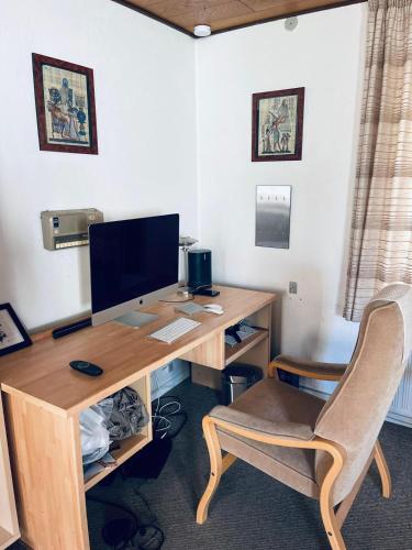 a desk with a computer monitor and a chair at VS-Homestay in Sakskøbing
