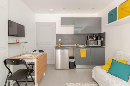 une petite cuisine avec une table et un canapé dans l'établissement Logement prive et calme EUREXPO Groupama Stadium TRAM Parking Terasse, à Saint-Priest