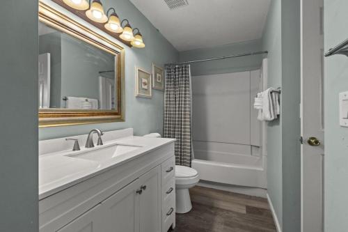 a bathroom with a sink and a toilet and a mirror at SeaCove Steps 2 Priv Beach Backyard Comm Pool in Destin