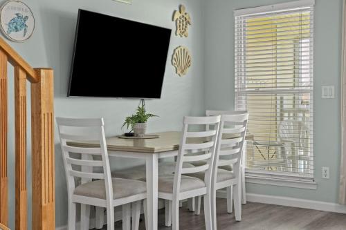 a dining room with a table and white chairs at SeaCove Steps 2 Priv Beach Backyard Comm Pool in Destin