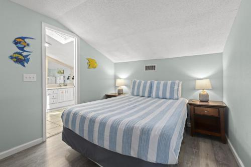 a bedroom with a bed with a blue and white striped sheets at SeaCove Steps 2 Priv Beach Backyard Comm Pool in Destin