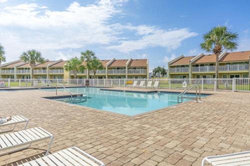 a swimming pool with chairs and palm trees in a resort at SeaCove Steps 2 Priv Beach Backyard Comm Pool in Destin
