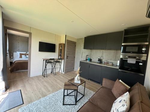 a living room with a couch and a kitchen at Logement cosy indépendant avec jardin et Parking in Cornillé