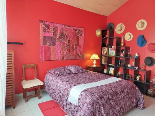 - une chambre avec des murs rouges, un lit et une chaise dans l'établissement SABLE BLEU, maison d'architecte, à Andernos-les-Bains