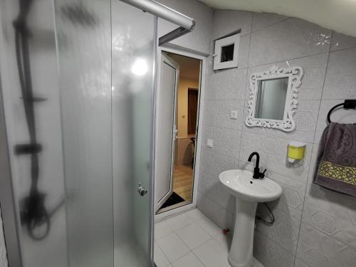 a white bathroom with a sink and a shower at Guest House Natia in Tbilisi City
