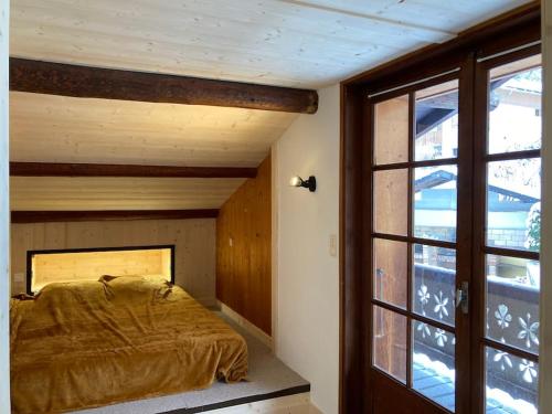 une chambre avec un lit et une grande fenêtre dans l'établissement Chalet accueillant avec cheminée à 5 min du centre, à Saint-Gervais-les-Bains