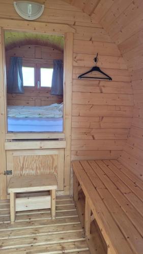 a wooden cabin with a bench and a window at Schlaffass in Grevenkop