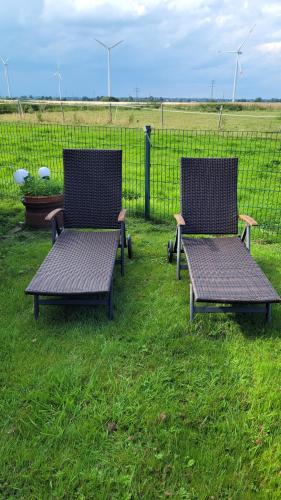 two benches sitting in the grass next to a fence at Schlaffass in Grevenkop