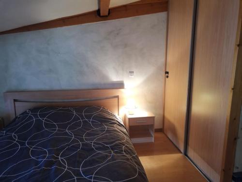 a bedroom with a bed and a lamp on a table at Le charme montagnard in Barcelonnette