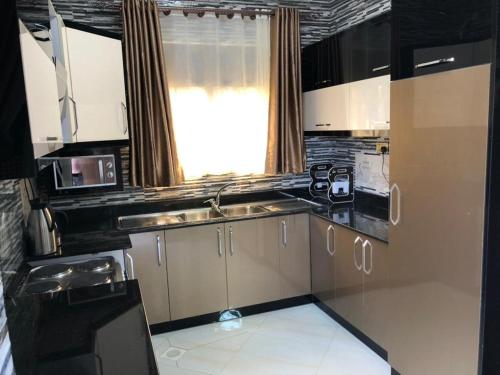 a kitchen with white cabinets and a sink and a window at Jengel Double bedroom Furnished Apartment in Entebbe
