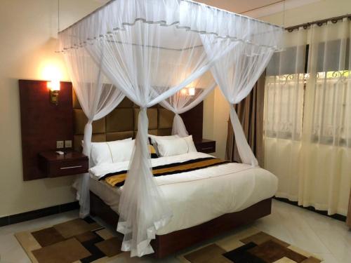 a bedroom with a canopy bed with white curtains at Jengel Double bedroom Furnished Apartment in Entebbe