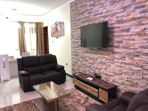 a living room with a couch and a tv on a brick wall at Jengel Double bedroom Furnished Apartment in Entebbe