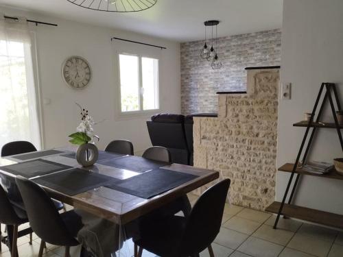 a dining room table with chairs and a clock on the wall at Gîte le Vieux Moulin in Sansais