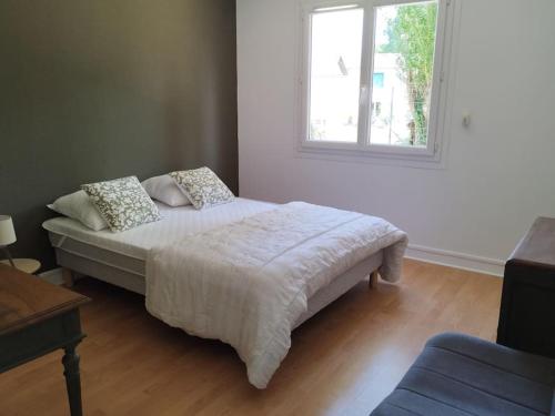 a bedroom with a white bed with a window at Gîte le Vieux Moulin in Sansais