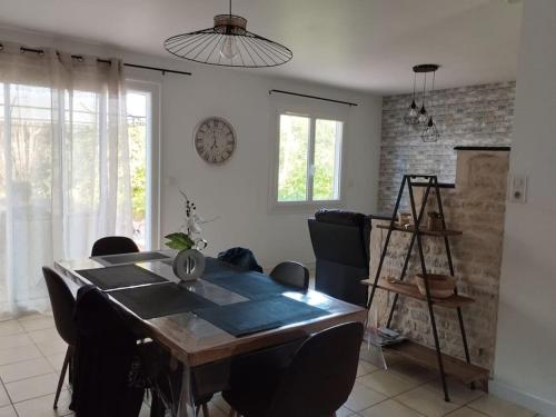 a dining room table with chairs and a clock on the wall at Gîte le Vieux Moulin in Sansais