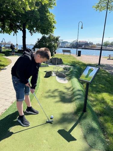 a boy is playing golf in a park at Badholmen Restaurang & Hotell in Oskarshamn