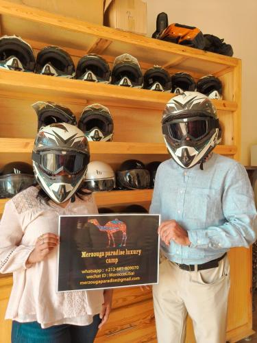two people wearing helmets holding a sign in a store at Merzouga Paradise Luxury Camp in Merzouga