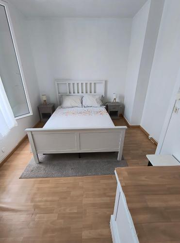 - une chambre avec un lit blanc et du parquet dans l'établissement Jolie Appartement maison très bien placé, à Épinay-sur-Seine