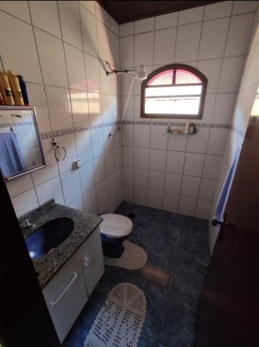 a bathroom with a sink and a toilet and a window at Casa vila do serrano in São Bento do Sapucaí