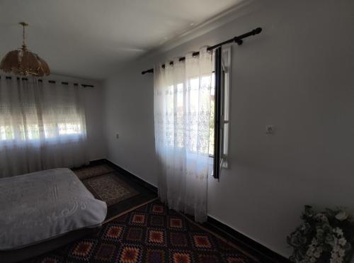 ein Schlafzimmer mit einem Bett und einem Fenster mit Vorhängen in der Unterkunft Cozy Room in the Old Town in Gjirokastër