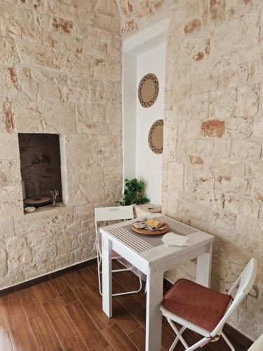 a white table and chairs in a room with a stone wall at PietraRosa Apartment in Triggianello