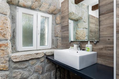 マリンスカにあるStone house Villa Liviaの石壁のバスルーム(白い洗面台付)