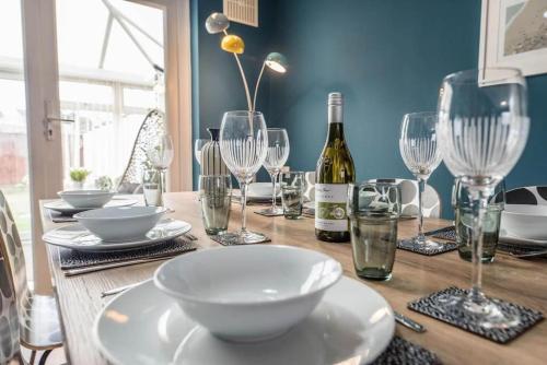a wooden table with glasses and a bottle of wine at Beautiful Aldeburgh Coastal Getaway in Aldeburgh