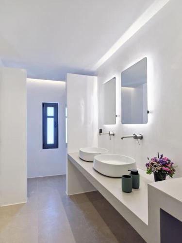 a white bathroom with two sinks and mirrors at Villa Sol Cielo Naousa Paros in Naousa
