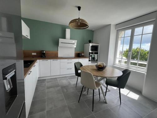 une cuisine avec une table et des chaises dans une cuisine dans l'établissement Maison de charme avec vue mer et jardin, à Plouhinec