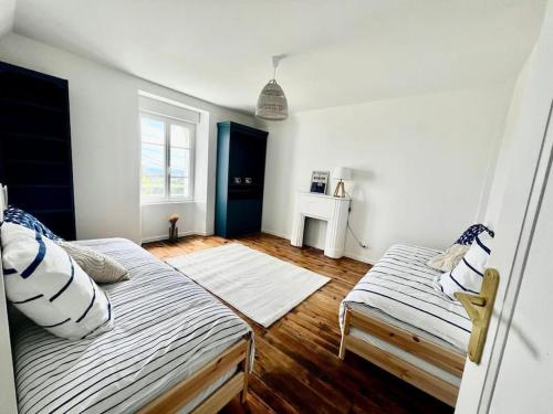 une chambre avec deux lits et une fenêtre dans l'établissement Maison de charme avec vue mer et jardin, à Plouhinec