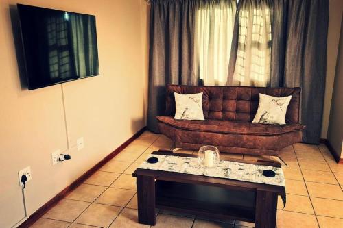 ein Wohnzimmer mit einem braunen Sofa und einem Tisch in der Unterkunft Cheerful 3-bedroom vacation home in Kathu