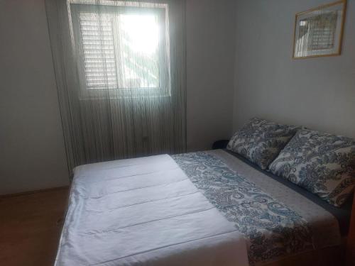 a bed in a bedroom with a window and a bedspread at Sandra Apartmani 1 in Zaostrog