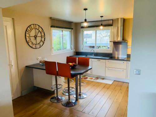 une cuisine avec une table et une horloge au mur dans l'établissement Family House near Paris & Normandy, aux Mureaux